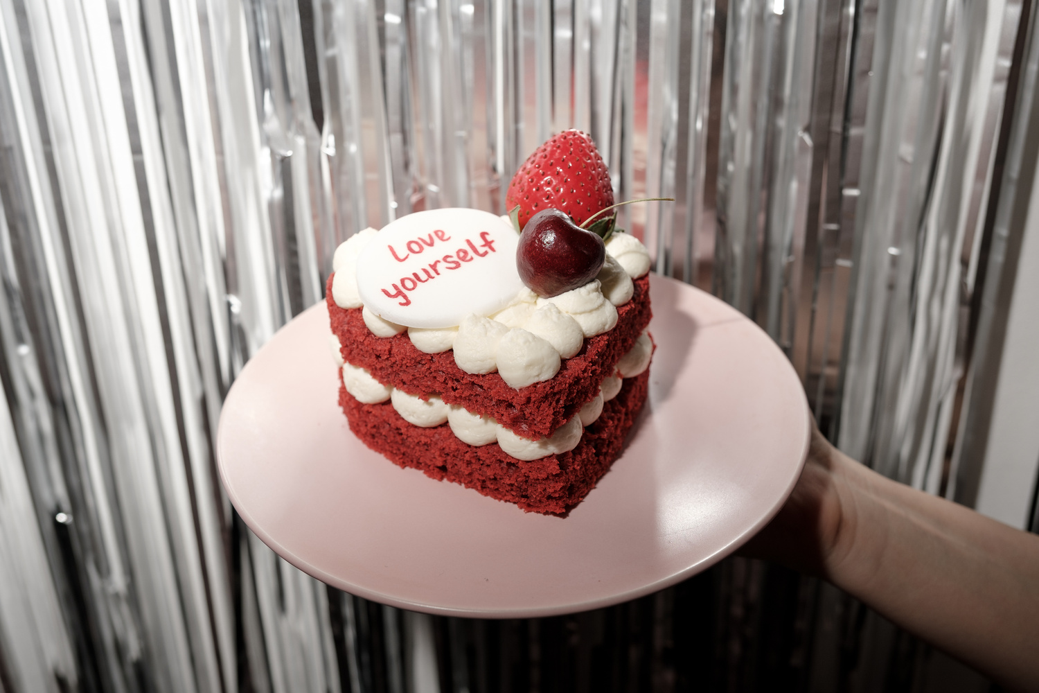 Hand Holding Heart-Shaped Red Velvet Cake